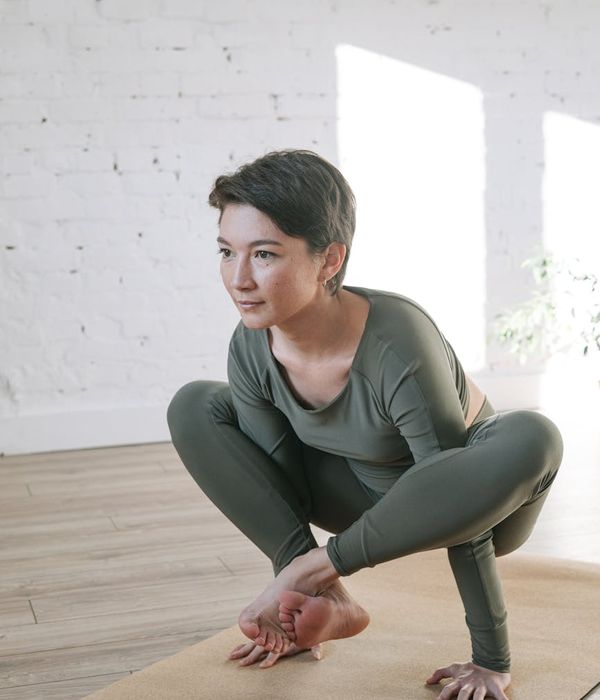 Woman performing a calm yoga pose in a bright, airy room.
